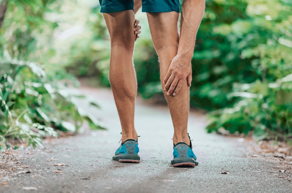 Mann in kurzen Jogginghosen fasst sich an seine schmerzende Waden; Symbolbild für Magnesiummangel